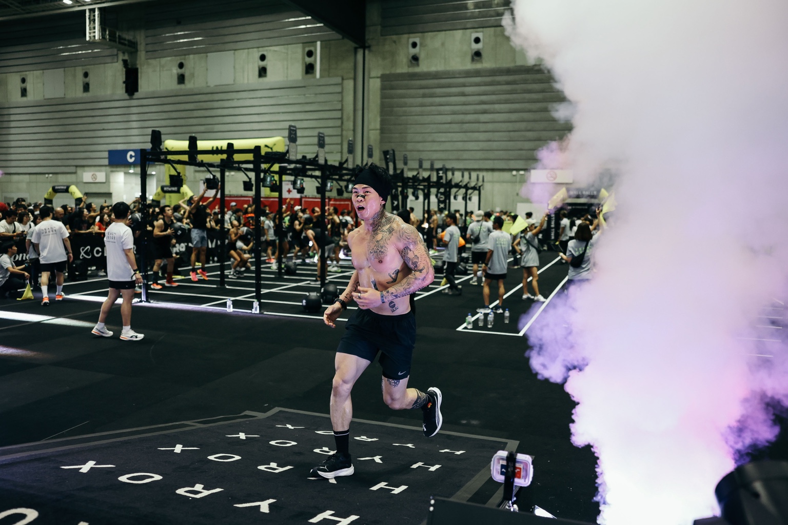 Edison Ho running through a HYROX finish with purple smoke