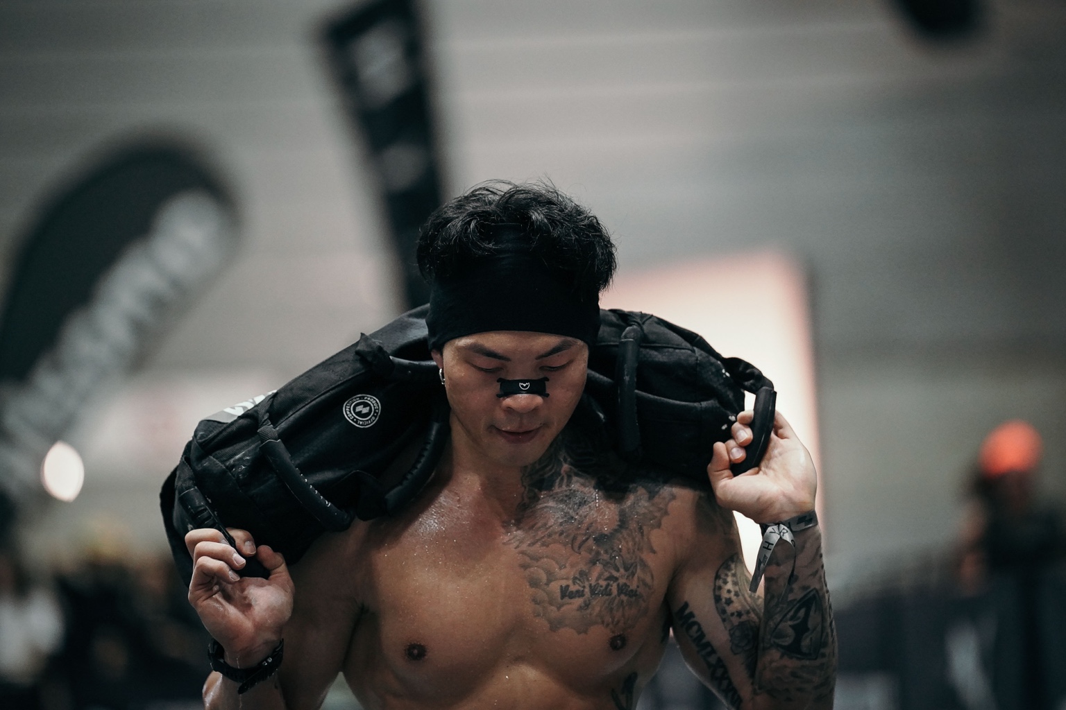 Edison Ho carrying a sandbag during a HYROX race